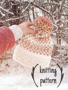 a hand holding a knitted hat in the snow