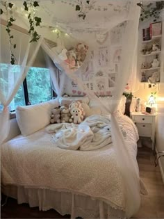 a white bed covered in lots of pillows and blankets next to a window with curtains