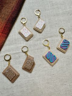 four different shaped key chains sitting next to each other on top of a piece of cloth