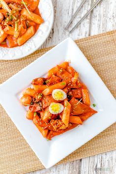 carrots with sesame seeds and an egg in the middle on a white square plate