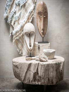 two wooden masks sitting on top of a table next to a pile of cloths