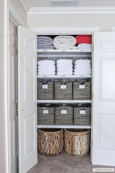 an organized closet with baskets and towels