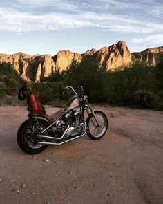 a motorcycle parked in the desert with mountains in the background