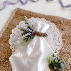 a napkin with flowers on it sitting on top of a place mat next to a purple ribbon