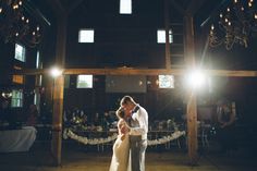 a bride and groom sharing their first dance at their wedding reception in the great barn