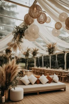 a couch with pillows and lights hanging from it's ceiling in front of a tent