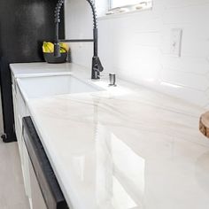 a kitchen with white counter tops and black faucet