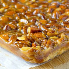 a close up of a piece of food on a cutting board with nuts and caramel