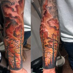 a man's arm with trees and clouds on it