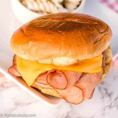 a close up of a sandwich on a plate near a bowl of macaroni and cheese