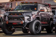 a gray toyota truck parked in front of a building with other trucks behind it on display