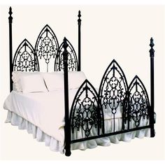 a black iron bed with white sheets and pillows