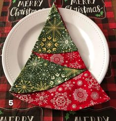 a white plate topped with a green and red christmas tree napkin on top of a table