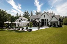 a large white house sitting on top of a lush green field next to a swimming pool