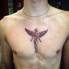 a man with a tattoo on his chest has a cross and angel design on it