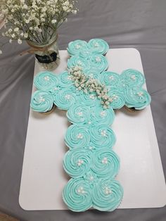 a cupcake shaped like a cross sitting on top of a white tray with flowers