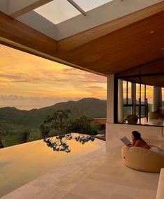 a woman sitting on top of a bean bag chair next to a swimming pool at sunset