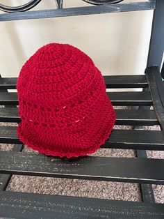 a red knitted hat sitting on top of a wooden bench