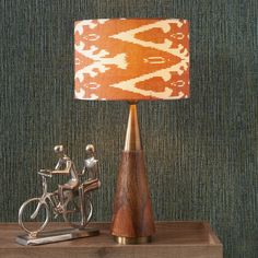 a lamp sitting on top of a wooden table next to a figurine riding a bike