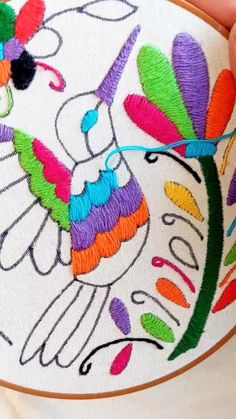 someone is stitching an embroidered design on a white piece of cloth with colorful thread