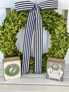 a green wreath with black and white striped ribbon, two small blocks sitting next to it