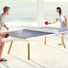 two people playing ping pong on the beach