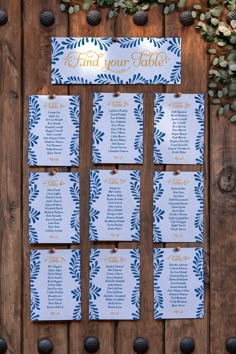 wedding seating cards with pine cones and greenery on the side of a wooden wall