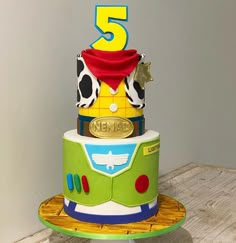 a three tiered birthday cake decorated with toy story characters and number 5 on top