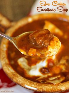 a spoon full of soup with meat and cheese in it on a red and white plate