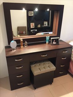 a dresser with a mirror and stool underneath it