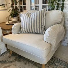 a chair with two pillows on it in front of a window