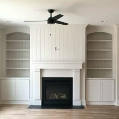 an empty living room with a fireplace and built - in bookcases