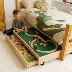 a child playing with a train set in a bed frame that is built into the floor