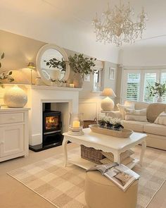 a living room filled with furniture and a fire place under a chandelier in front of a window