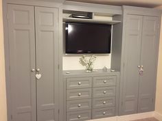 a flat screen tv mounted to the side of a gray cabinet in a living room