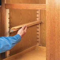 a person is opening the door with a pair of scissors in front of them on a wooden shelf