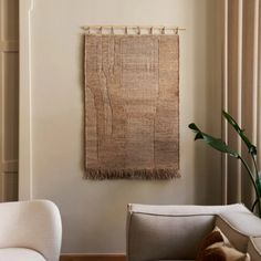 a living room with two white chairs and a rug on the wall in front of it