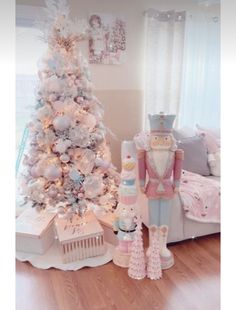 a white christmas tree with pink and blue decorations in a living room next to a bed