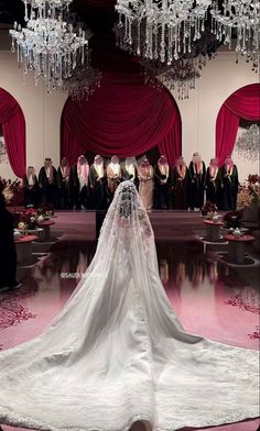 the bride is walking down the runway in her wedding dress and veil with crystal chandeliers hanging from the ceiling