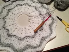 a crocheted doily with yarn and scissors on a table next to it