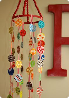 a red letter hanging from the side of a wall next to a colorful wind chime