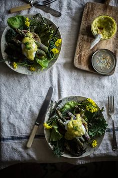 two plates filled with food sitting on top of a table next to utensils