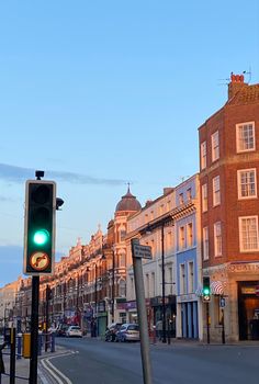 a green traffic light sitting on the side of a road next to tall brick buildings