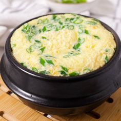 an omelet in a black bowl on a wooden table next to other dishes