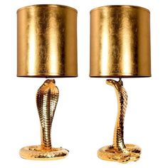 two gold cobra lamps with shades on them