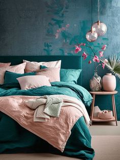 a bedroom with teal and pink bedding in the corner, green wall behind