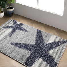 a blue and white rug with a star design on the floor next to a potted plant