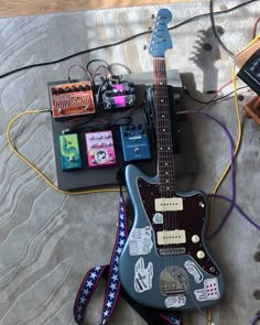 an electric guitar sitting on top of a bed next to other electronic devices and cords