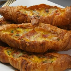 three croissants on a white plate topped with melted cheese and toppings