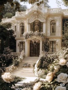 a large white house with lots of flowers on the front and stairs leading up to it